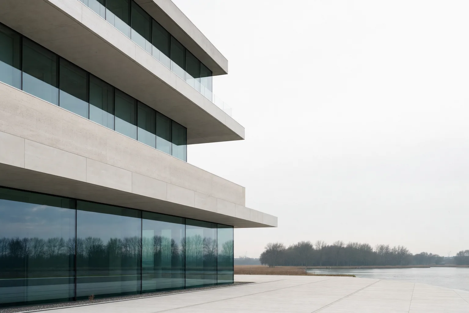 Rustige moderne bedrijfsgevel van beton en glas bij zacht daglicht aan het water